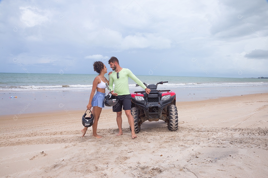 Casal curtindo férias andando de quadriciclo sobre dunas