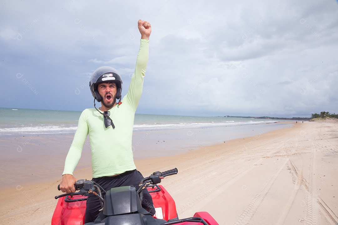Homem jovem curtindo férias andando de quadriciclo sobre dunas