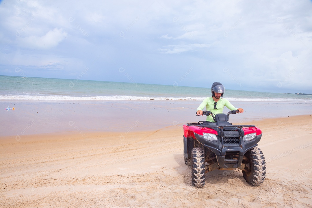Homem jovem curtindo férias andando de quadriciclo sobre dunas
