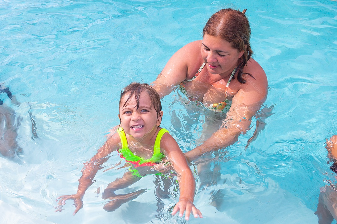 Mãe brincando com sua filha sobre piscina feliz férias família