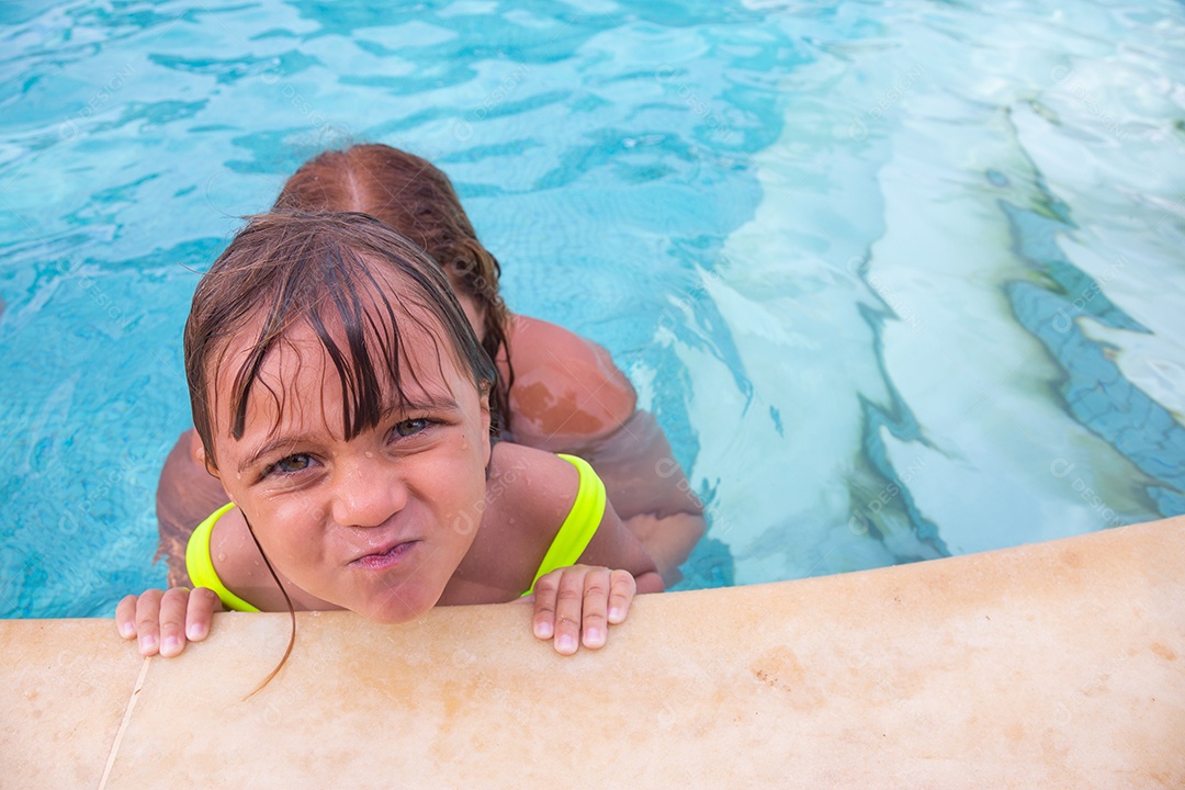 Mãe brincando com sua filha sobre piscina feliz férias família