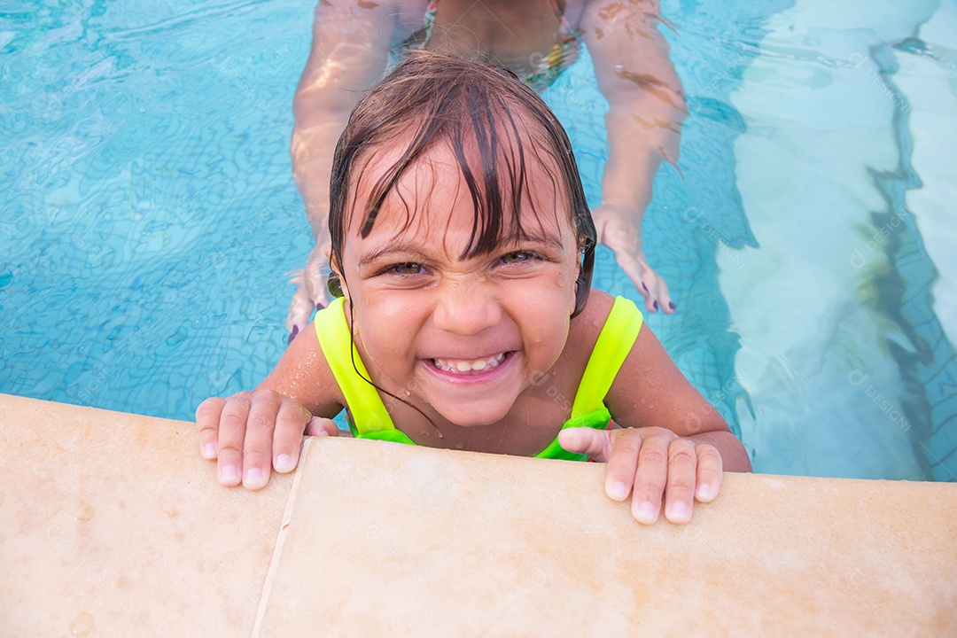 Mãe brincando com sua filha sobre piscina feliz férias família