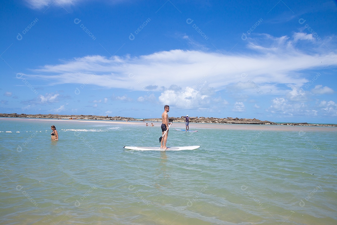 Homem jovem andando sobre prancha curtindo férias sobre uma praia