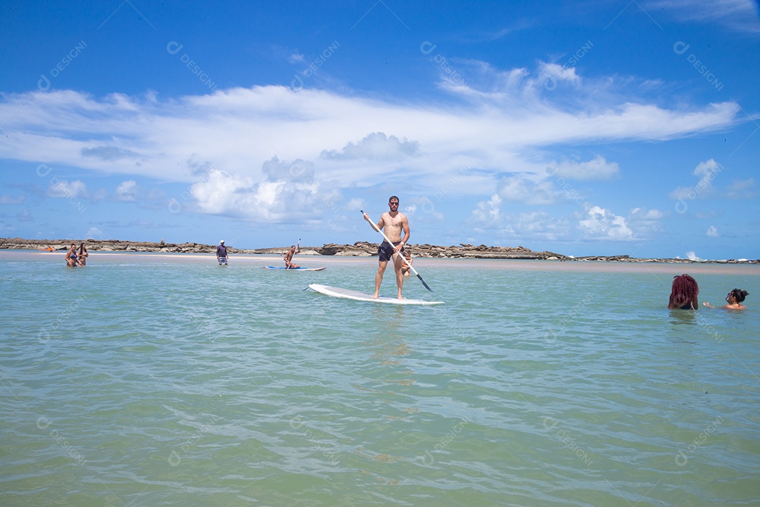 Homem jovem andando sobre prancha curtindo férias sobre uma praia