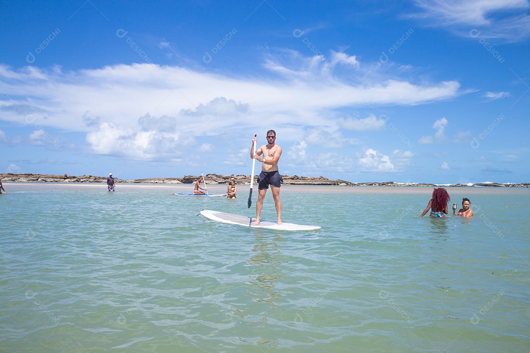 Homem jovem andando sobre prancha curtindo férias sobre uma praia