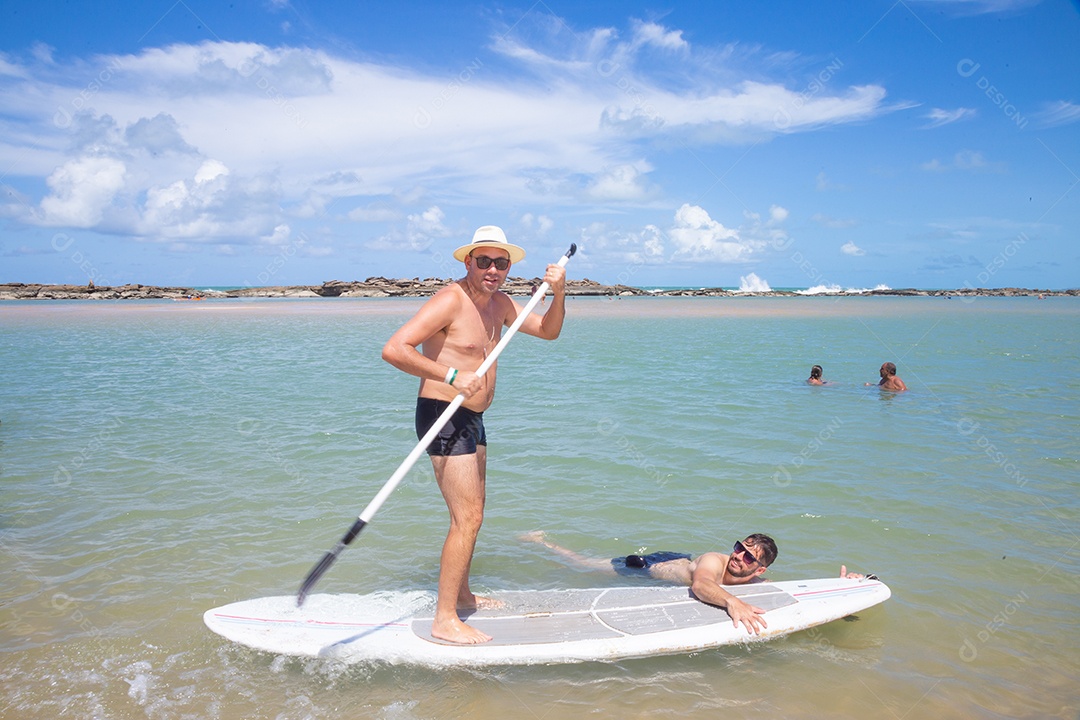 Elderly man walking on a surfboard enjoying vacation on a beach