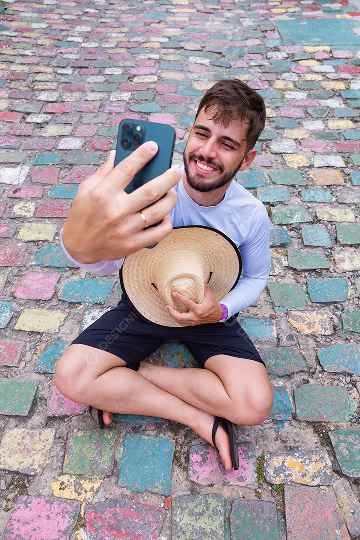 Homem jovem sentado no chão tirando fotos