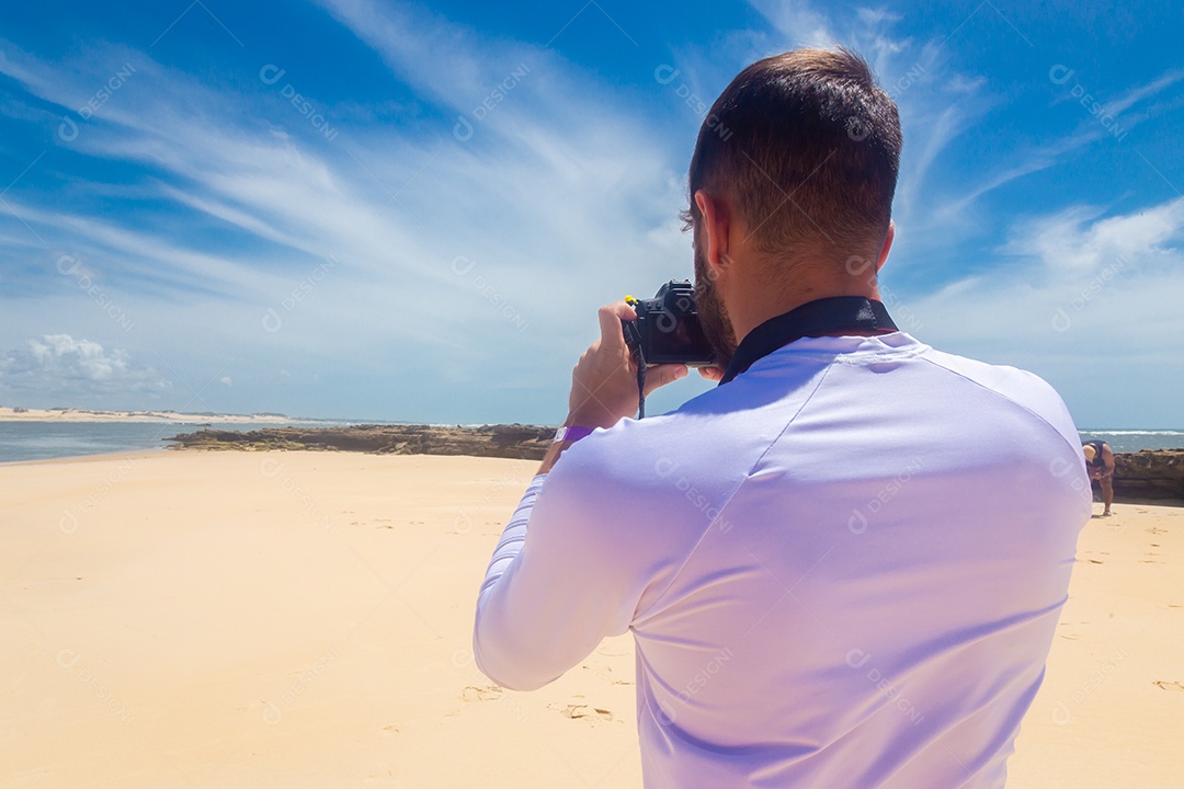 Homem jovem segurando câmera fotográfica fotografando praia
