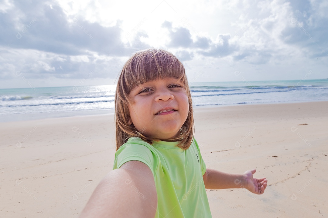 Linda garotinha tirando selfie usando trajes de banho sobre praia curtindo verão