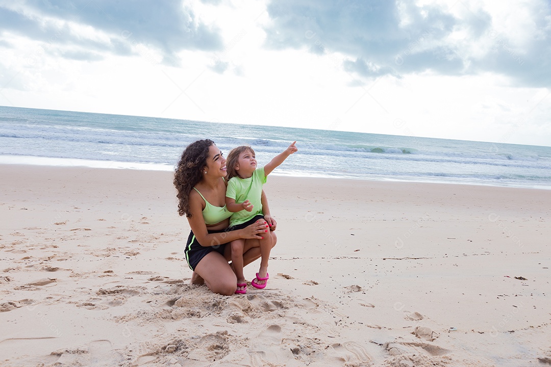Mãe brincando com sua filha sobre praia feliz férias família