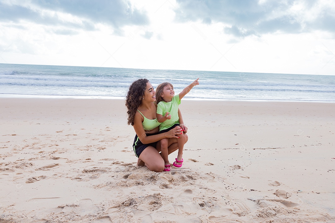 Mãe brincando com sua filha sobre praia feliz férias família