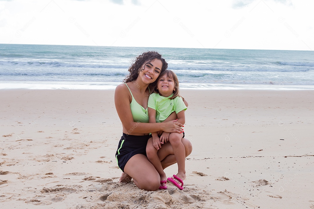 Mãe brincando com sua filha sobre praia feliz férias família