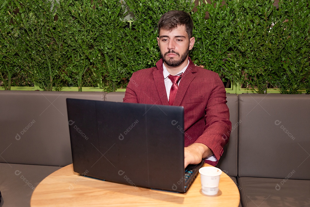 Homem jovem empresário usando terno mexendo em seu notebook