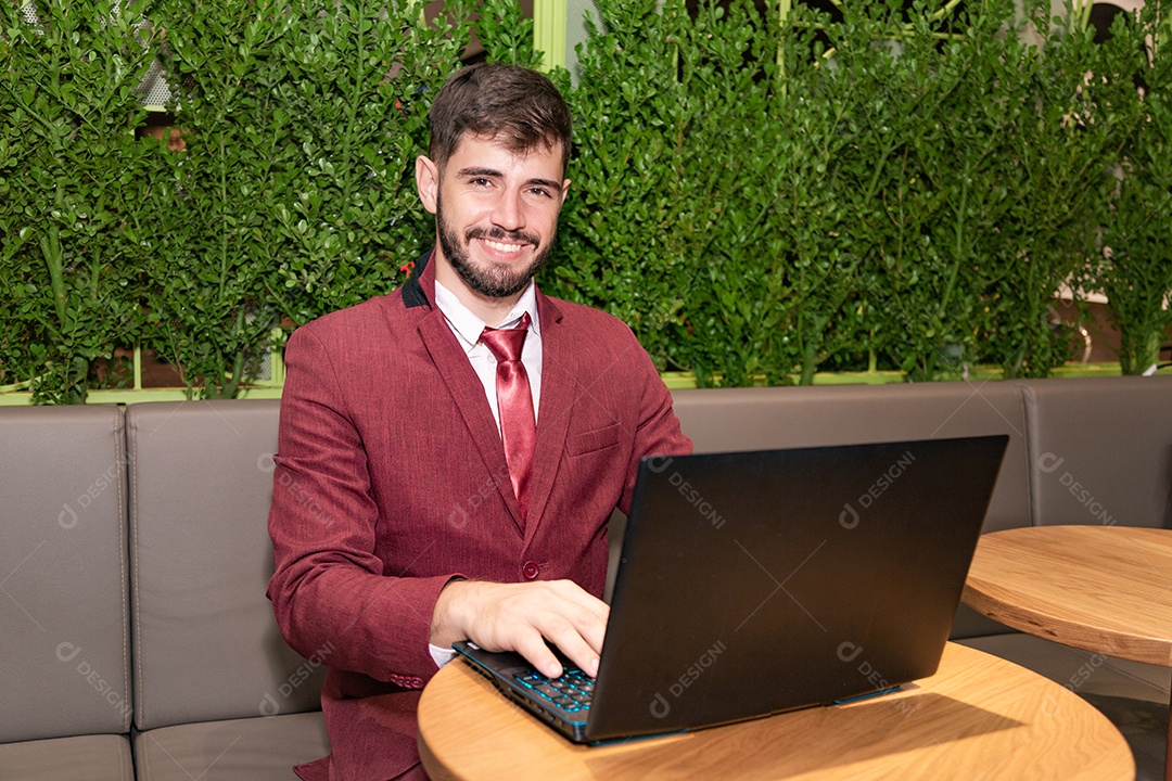 Homem jovem empresário usando terno mexendo em seu notebook