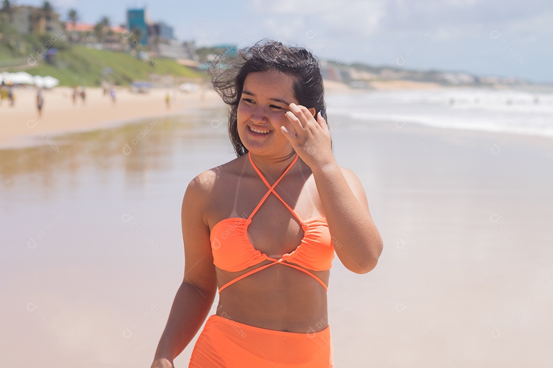 Mulher feliz usando biquíni laranja nadando no mar.