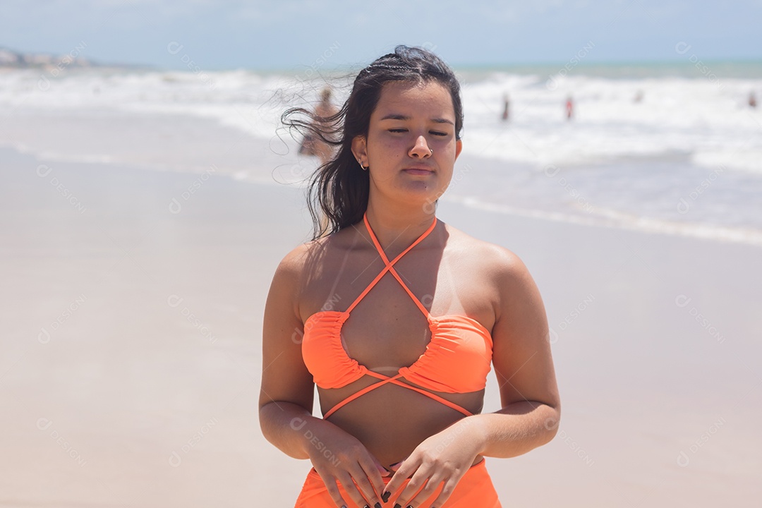 Mulher feliz usando biquíni laranja nadando no mar.