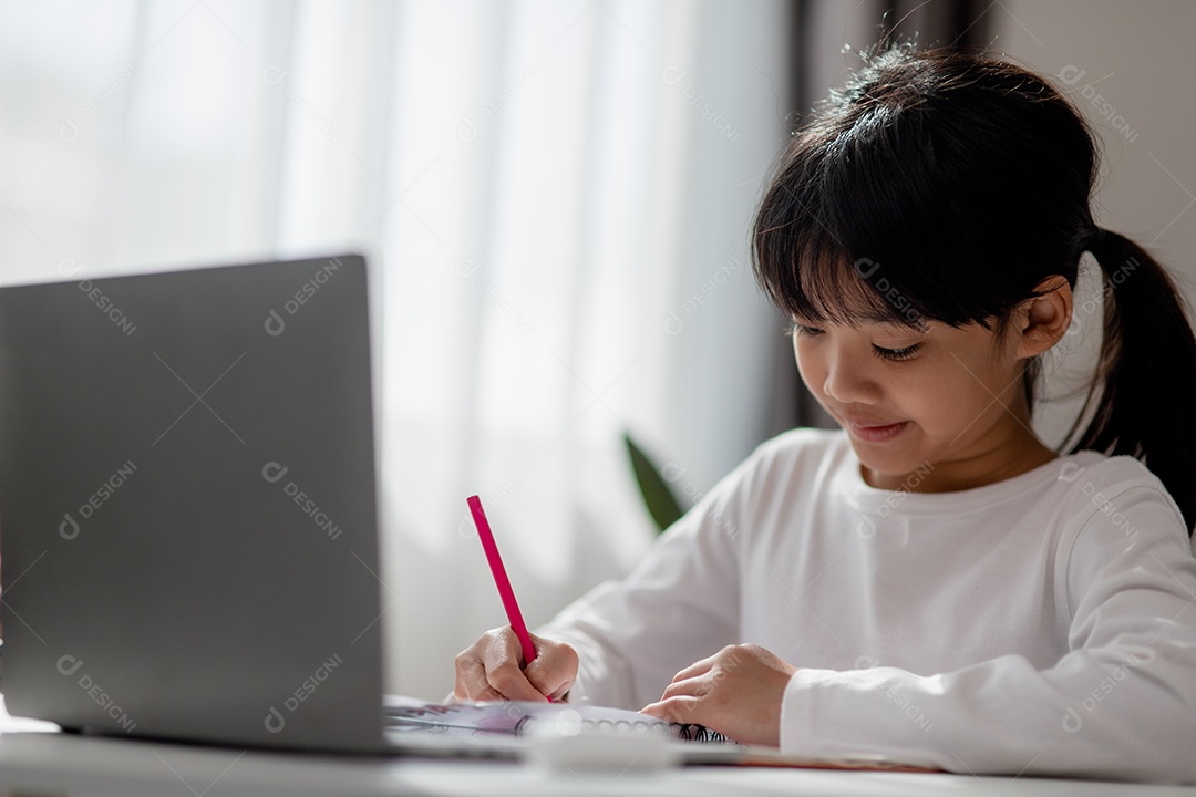 Aluna asiática fazendo sua lição de casa com o laptop em casa.