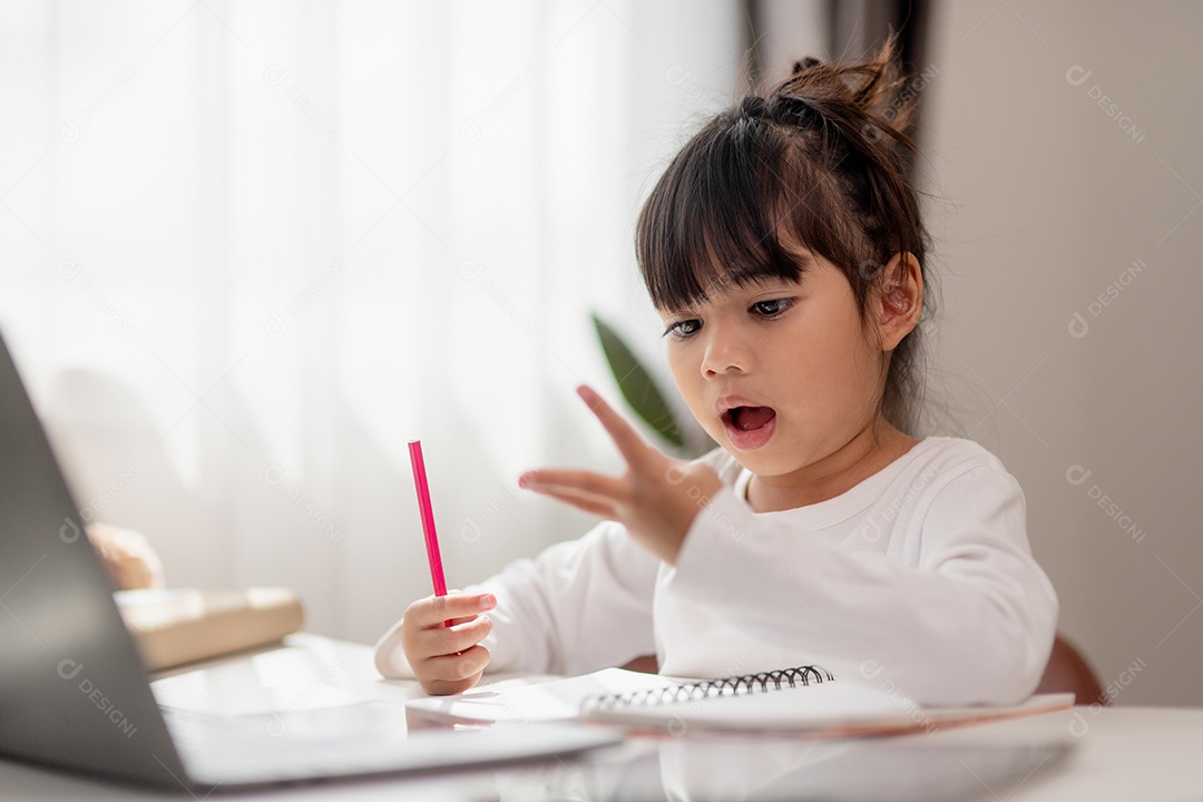 Aluna asiática fazendo sua lição de casa com o laptop em casa.