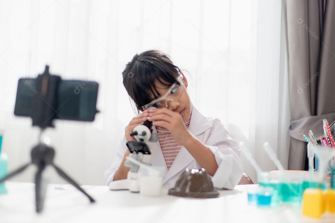 Menina da escola asiática fazendo experimentos de química fáceis e gravando.