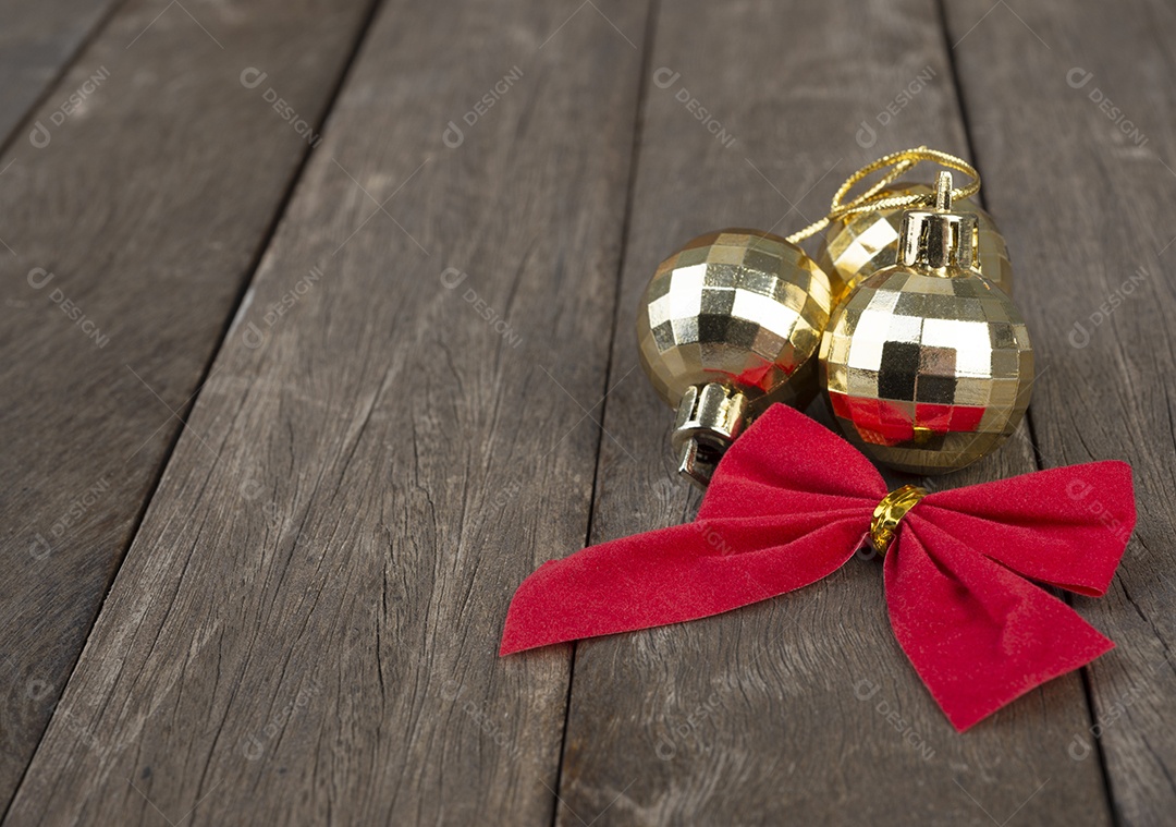 Bolas de natal douradas e laço vermelho de presente sobre a mesa de madeira.