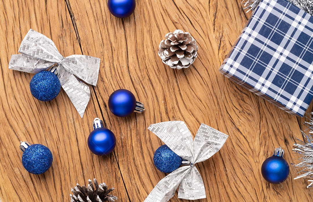 Caixa de presente, bolas de natal e arco sobre mesa de madeira.