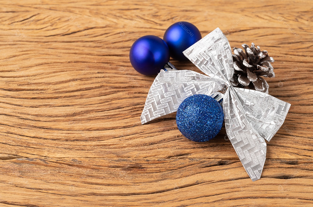 Bolas de natal, pinha e arco sobre mesa de madeira.