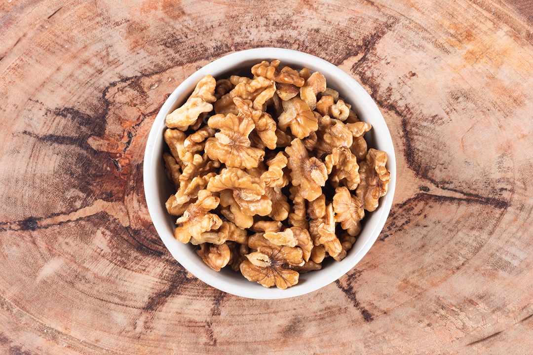 Tigela com nozes e vista superior de fundo de madeira.