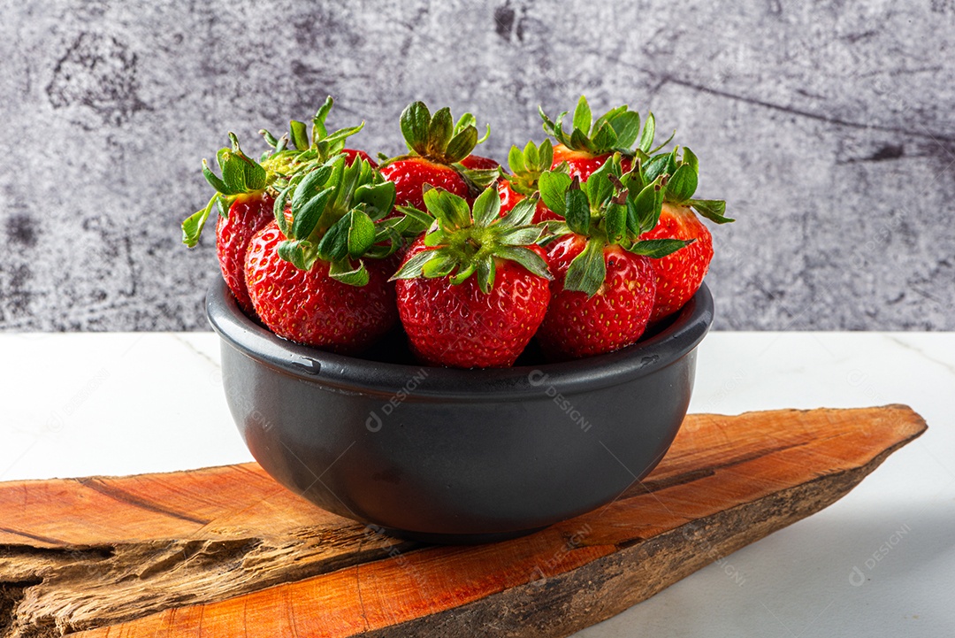 Sobremesa de morango servida em uma jarra em uma tábua de madeira e mármore