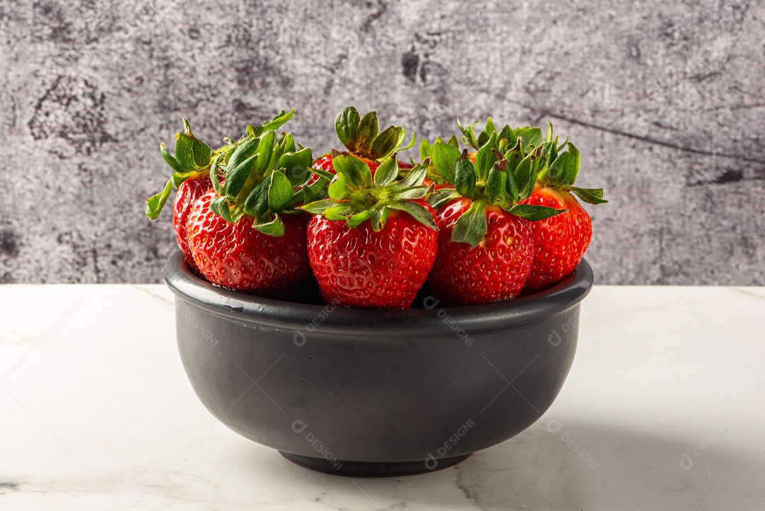 Sobremesa de morango servida em uma jarra em uma tábua de madeira e mármore