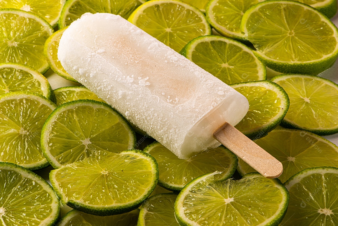 Picolé de Limão em fundo coberto de limão taiti cortados em rodelas