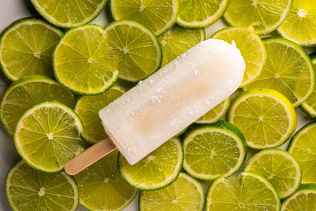 Picolé de Limão em fundo coberto de limão taiti cortados em rodelas