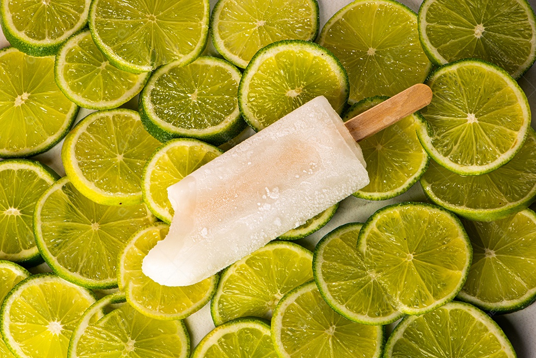 Picolé de Limão em fundo coberto de limão taiti cortados em rodelas