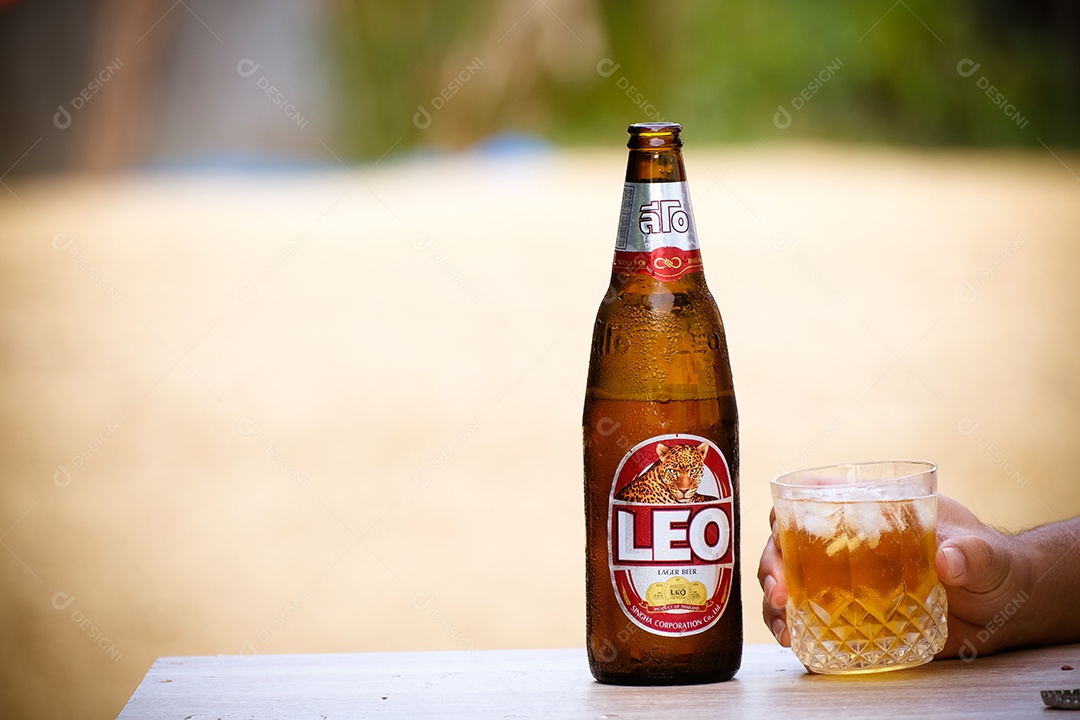 Mãos de pessoa pegando copo de cerveja garrafa long neck sobre uma mesa branca