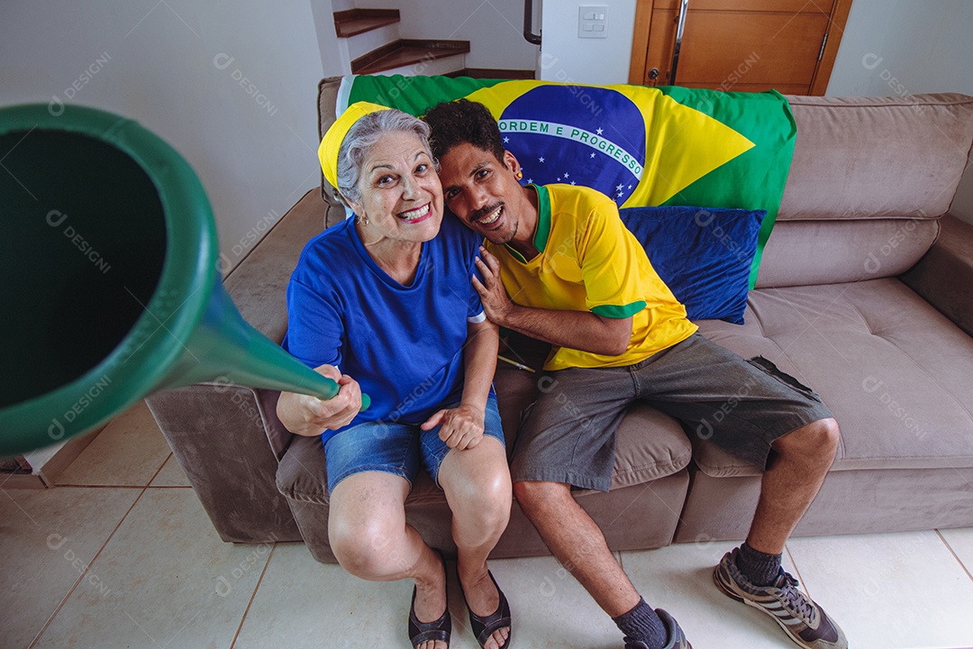 Mãe e filho comemorando a Copa na sala assistindo TV torcendo pelo Brasil. Família de raça mista tirando foto de selfie enquanto assistia ao jogo da copa.