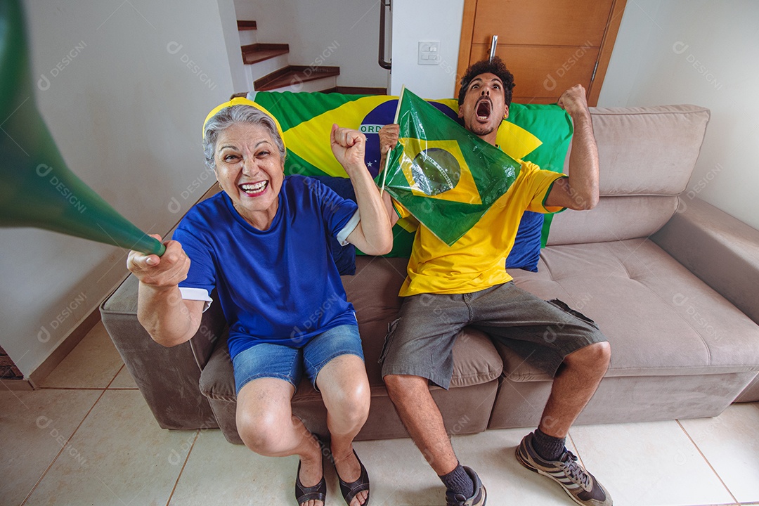 Mãe e filho comemorando a Copa na sala assistindo TV torcendo pelo Brasil. Família de raça mista tirando foto de selfie enquanto assistia ao jogo da copa.