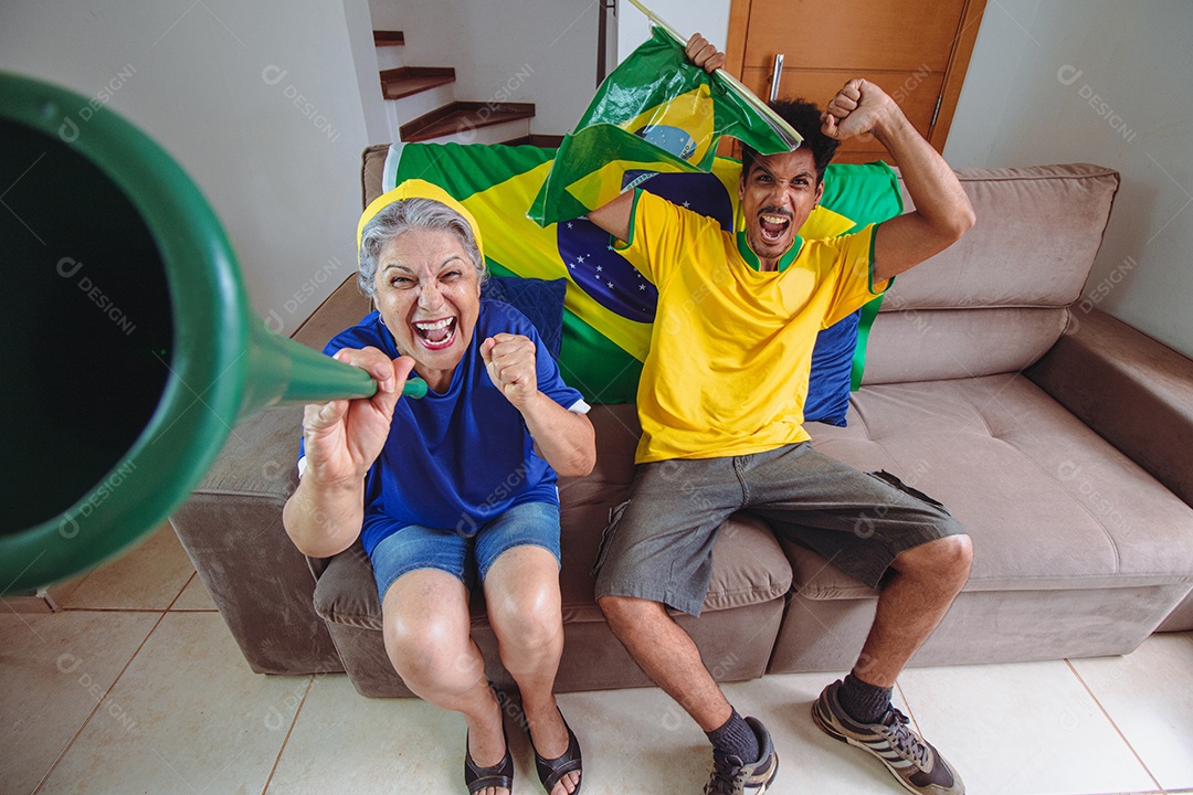 Mãe e filho comemorando a Copa na sala assistindo TV torcendo pelo Brasil. Família de raça mista tirando foto de selfie enquanto assistia ao jogo da copa.