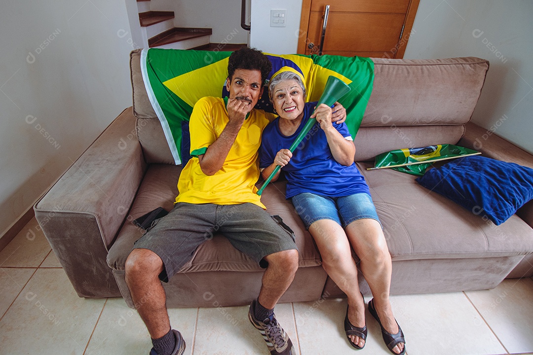 Mother and son celebrating the World Cup in the living room watching TV rooting for Brazil. Mixed race family taking selfie photo while watching cup game.