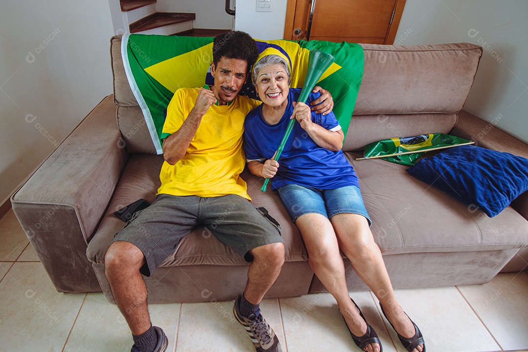 Mãe e filho comemorando a Copa na sala assistindo TV torcendo pelo Brasil. Família de raça mista tirando foto de selfie enquanto assistia ao jogo da copa.