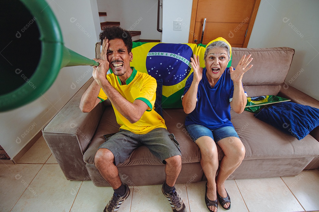 Mãe e filho comemorando a Copa na sala assistindo TV torcendo pelo Brasil. Família de raça mista tirando foto de selfie enquanto assistia ao jogo da copa.