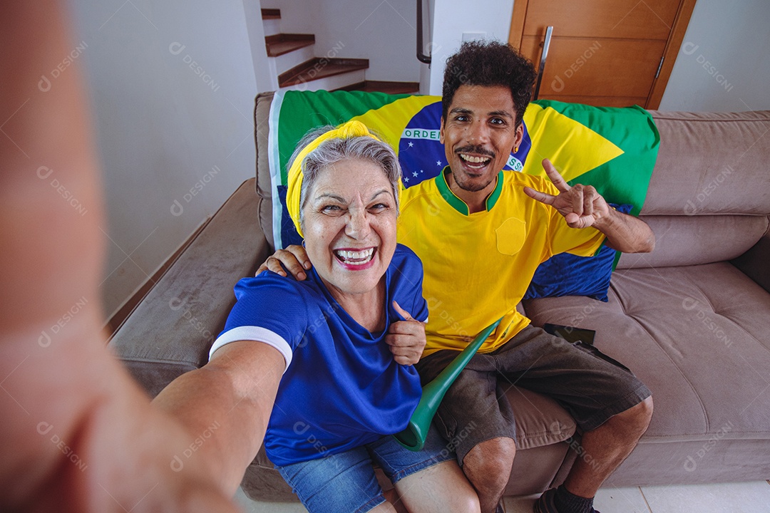 Mãe e filho comemorando a Copa na sala assistindo TV torcendo pelo Brasil. Família de raça mista tirando foto de selfie enquanto assistia ao jogo da copa.