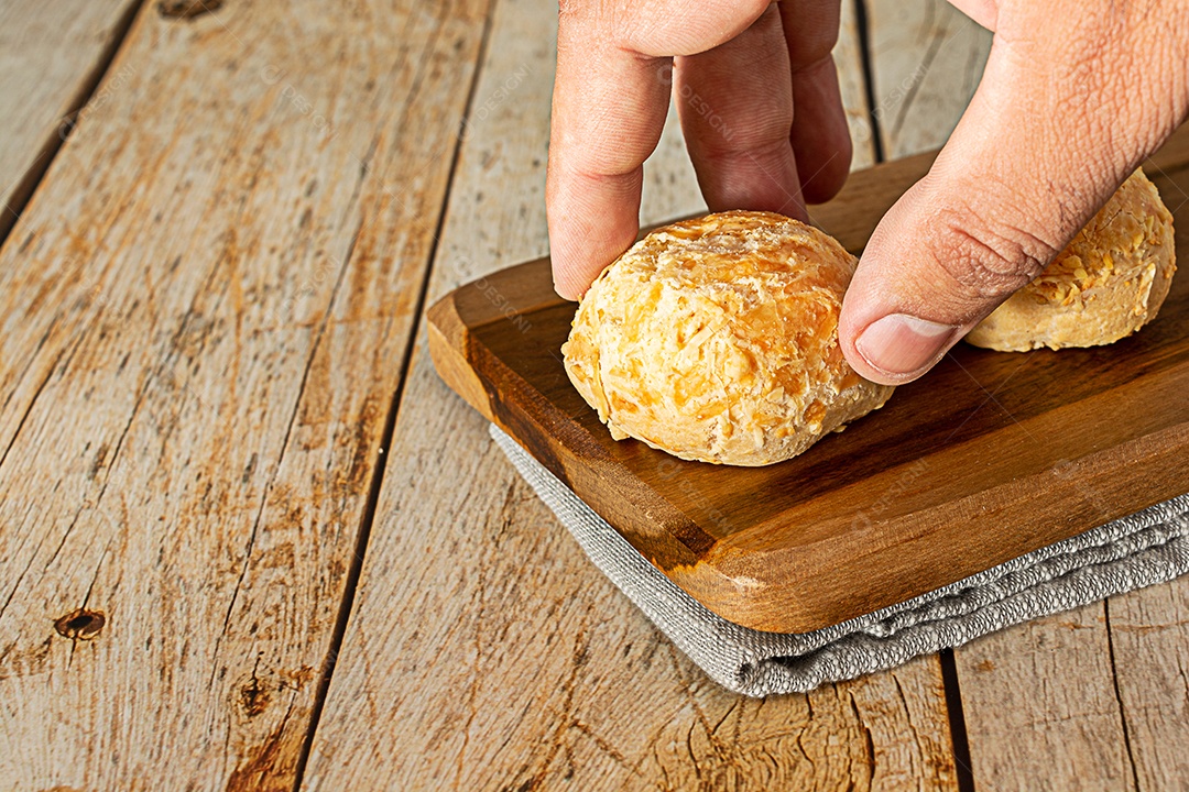 Mãos pegando pão de queijo, uma comida tradicional brasileira louca