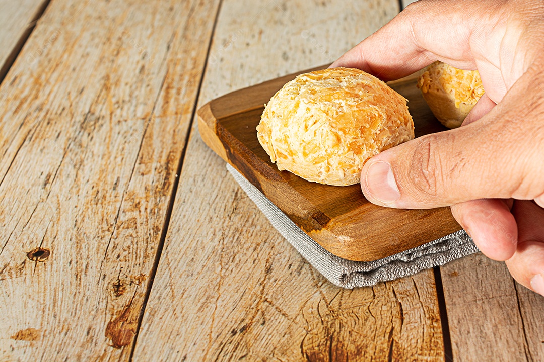 Mão pegando pão de queijo, uma comida tradicional brasileira