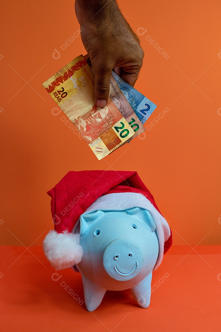 Moedas do cofrinho com chapéu de Natal de Papai Noel, painel solar fotovoltaico e lâmpada isolada em fundo laranja.