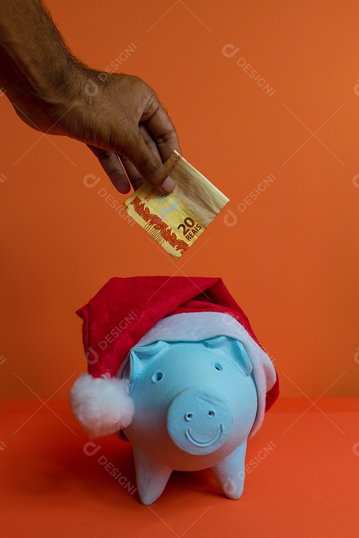 Moedas do cofrinho com chapéu de Natal de Papai Noel, painel solar fotovoltaico e lâmpada isolada em fundo laranja.