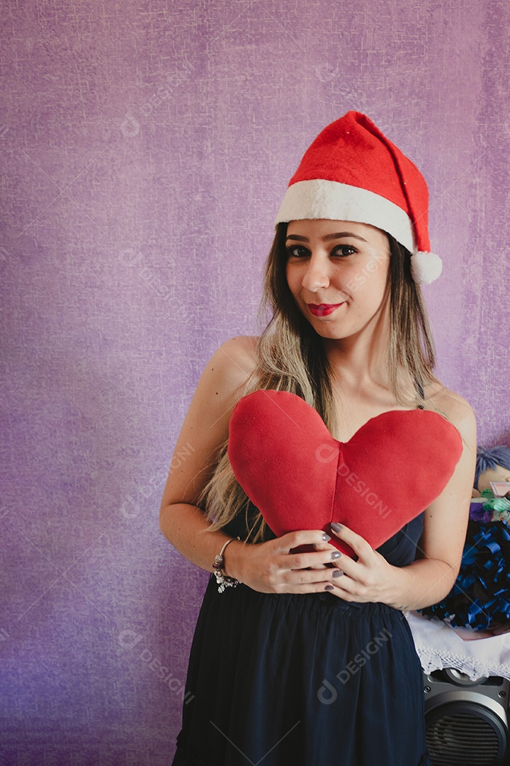 Retrato da linda e feliz Sra. Claus com chapéu de Natal segurando um presente de Natal. Isolado sobre um fundo roxo.