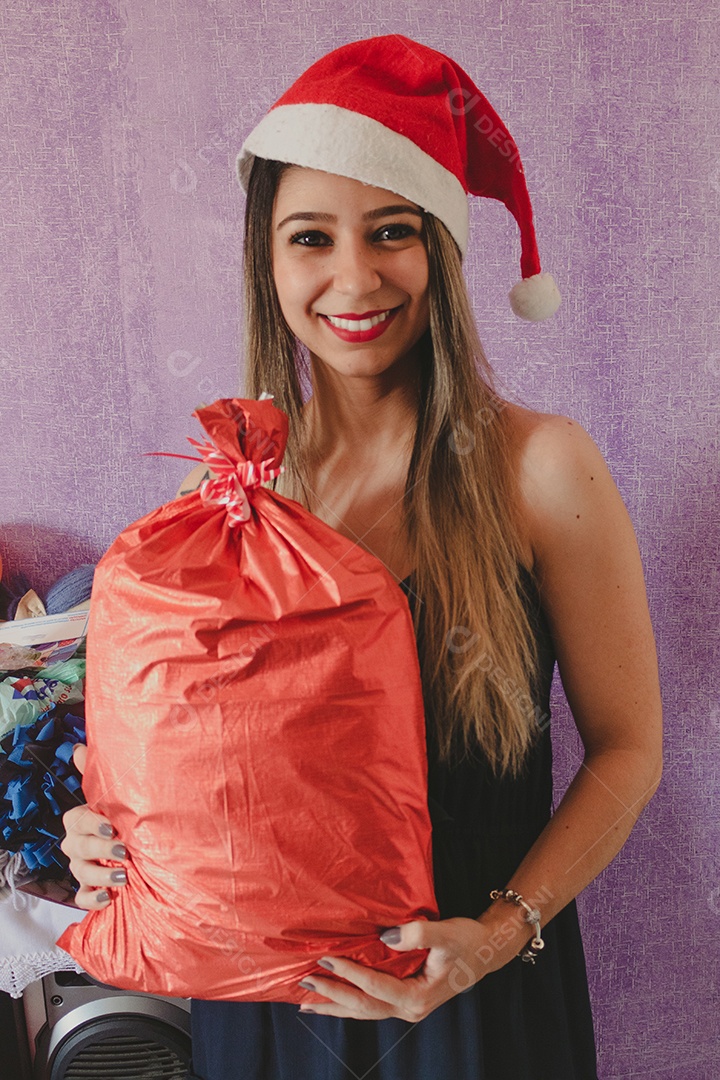 Retrato da linda e feliz Sra. Claus com chapéu de Natal segurando um presente de Natal. Isolado sobre um fundo roxo.