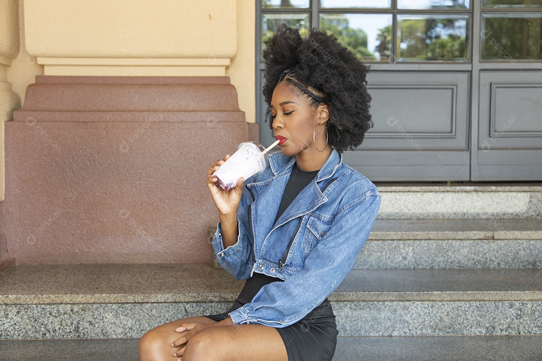 Linda mulher jovem negra cabelo afro cacheado tomando sorvete