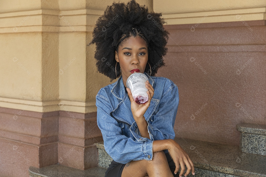 Linda mulher jovem negra cabelo afro cacheado tomando sorvete