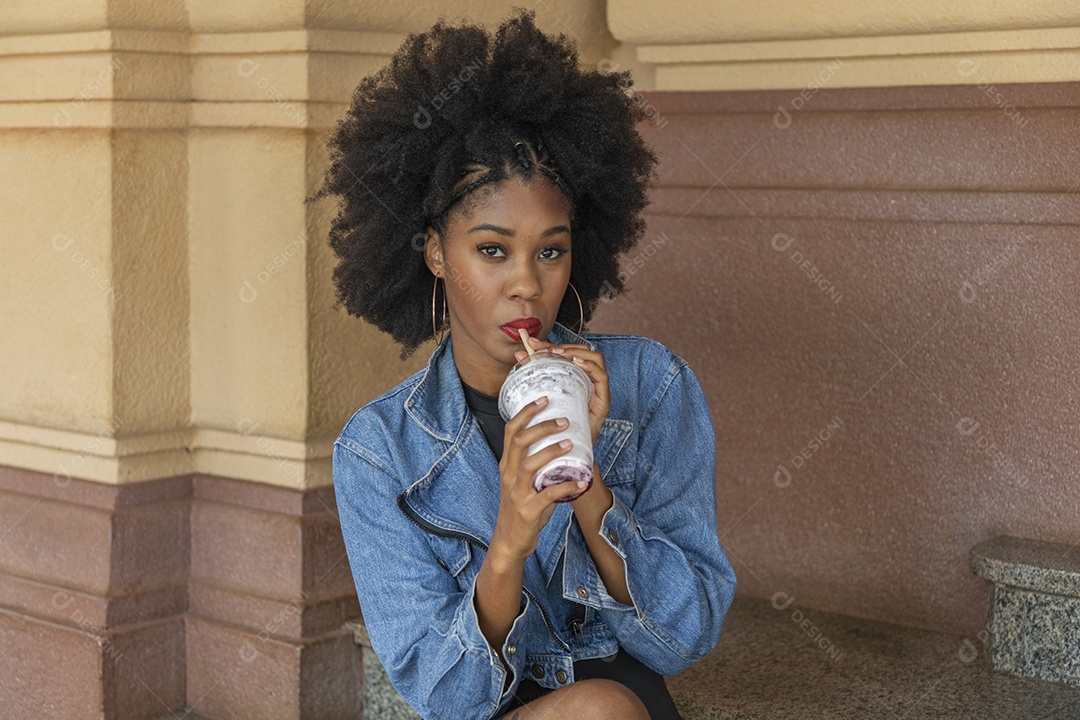 Linda mulher jovem negra cabelo afro cacheado tomando sorvete