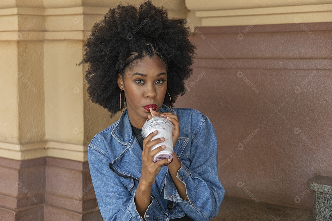 Linda mulher jovem negra cabelo afro cacheado tomando sorvete